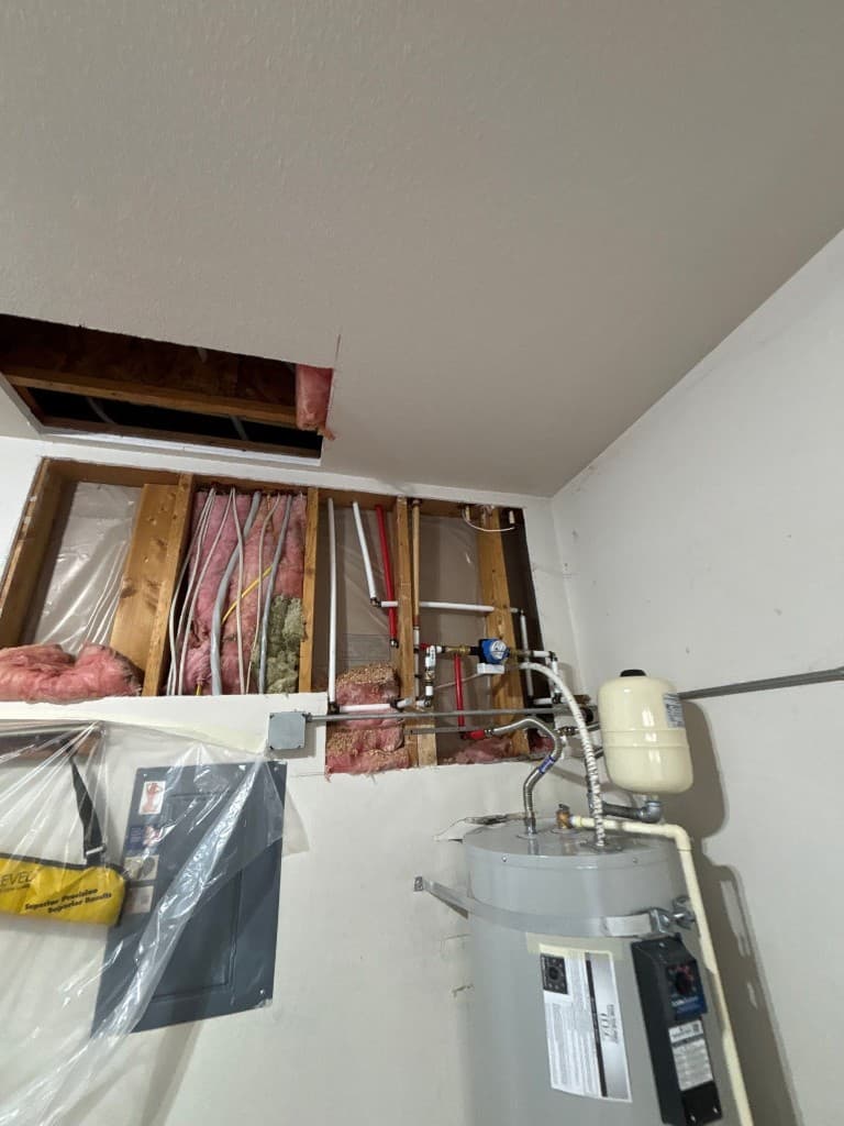 Mechanical wall with exposed piping and in-progress rough-in connections