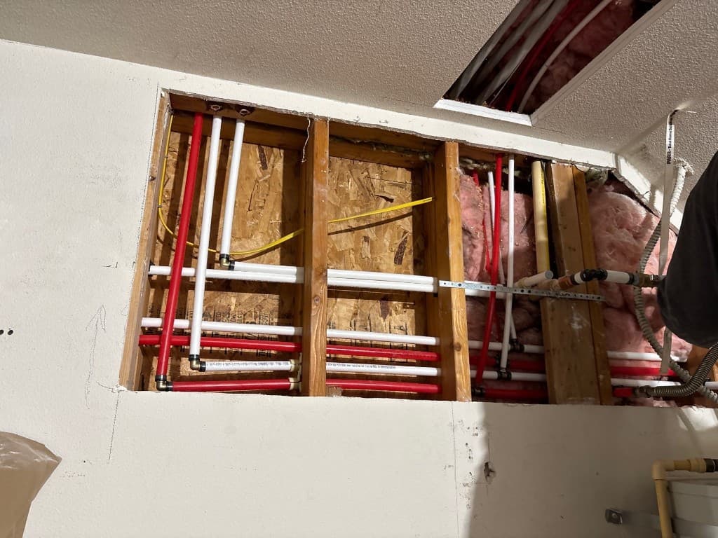 Open wall section showing multiple new hot and cold line routes during repipe project